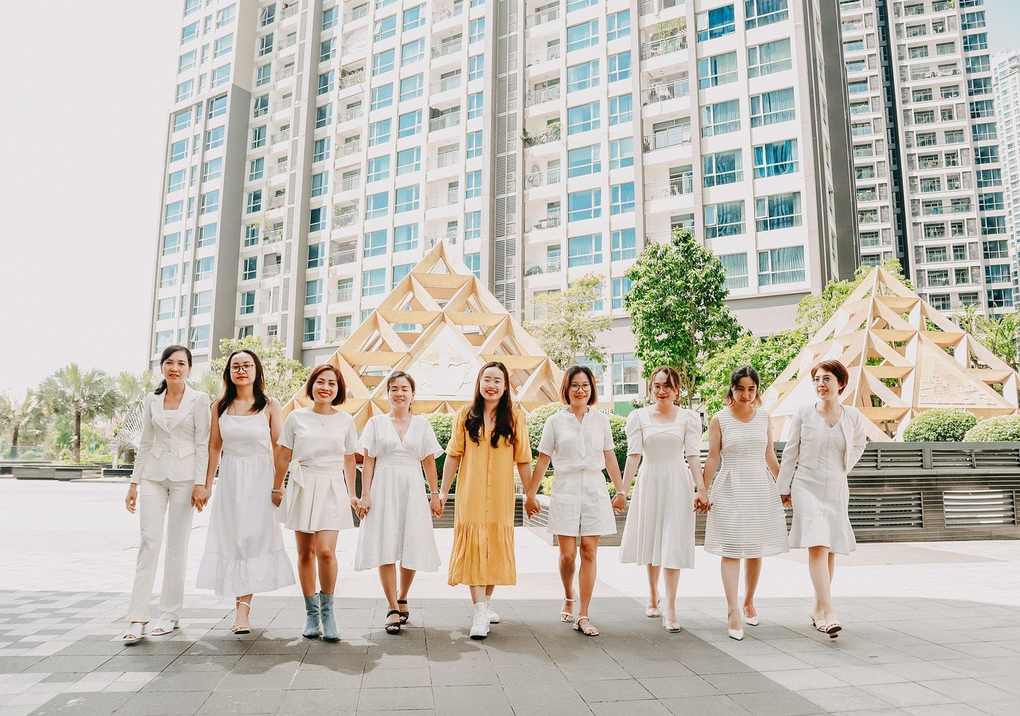 Huit femmes en blanc et une en jaune marchent main dans la main sur un trottoir Huit femmes en blanc et une en jaune marchent main dans la main sur un trottoir
