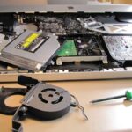 Ordinateur démonté sur une table avec outils et composants électroniques exposés