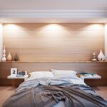 Un lit avec draps, tables de chevet, panneaux bois et fenêtre