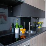 Cuisine contemporaine avec éléments en noir et gris, fruits et plantes décorant les surfaces