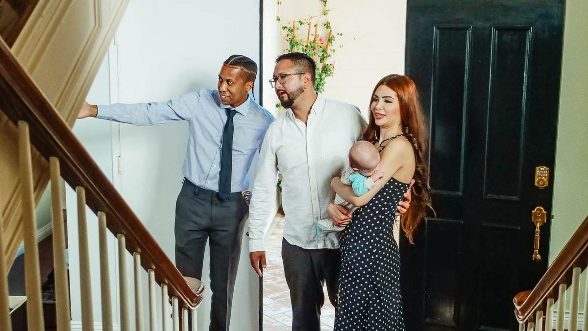Famille avec bébé et deux hommes dans une maison, près d'une escalier