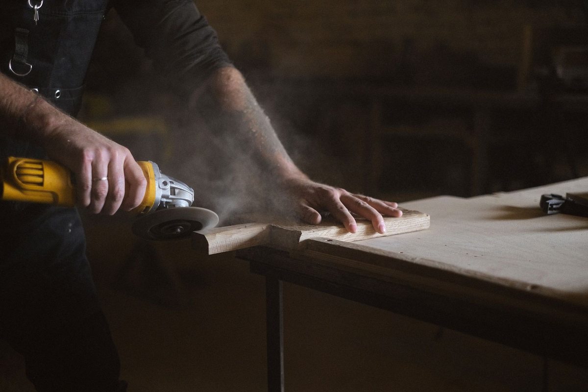 Personne utilisant une lime électrique sur une planche en bois dans un atelier Personne utilisant une lime électrique sur une planche en bois dans un atelier
