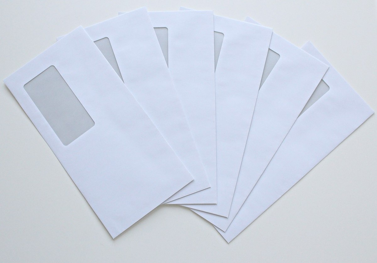 Plusieurs enveloppes blanches à fenêtre transparente disposées en éventail